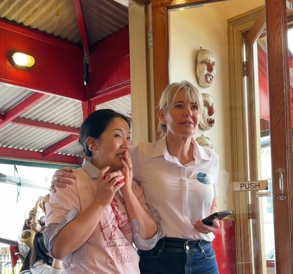 Speaker Sarina Gibbon, visibly moved, standing with the host by the cafe doors